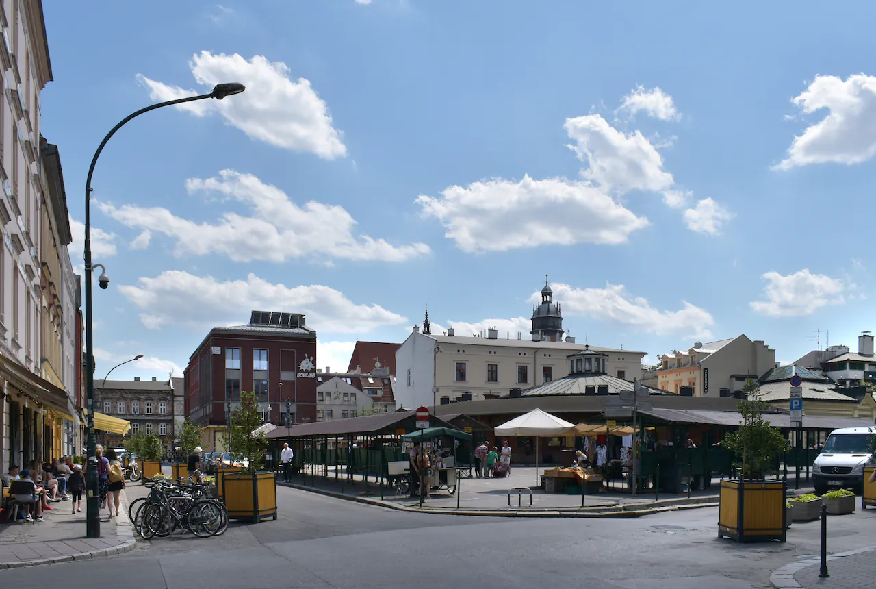 Plac Nowy na krakowskim Kazimierzu: okrągła hala targowa z budkami dookoła i kamienice w tle