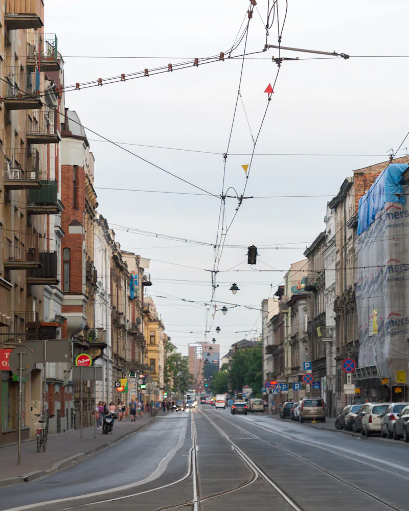 Ulica Starowiślna w Krakowie: kamienice po obu stronach, tory tramwajowe i sieć trakcyjna nad jezdnią